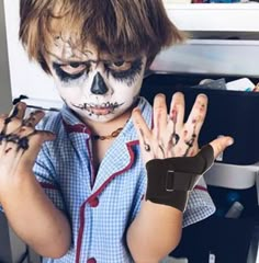 a young boy with face paint holding his hands in front of him and looking at the camera