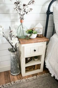 a bedroom with white walls and wood flooring is decorated with flowers, vases and books