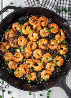 a skillet with shrimp and green onions in it