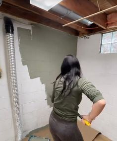 a woman is painting the walls in an unfinished room