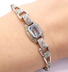 This iconic Art Deco dates from the 1920s. The bracelet is silver with a Synthetic Blue Spinel gemstone in the centre. The silver has a geometric design true of the period, with an intricate design on the silver. Marking: 835 AG. Size: 6 1/2 inches long (17 cm) Weight: 8 grams Condition: Fantastic condition. The clasp is working as it should. The stone is very bright with no damage. True flapper girl style bracelet. Find more unique Art Deco jewellery in my shop: https://www.etsy.com/uk/shop/per