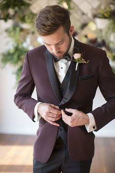 a man in a tuxedo adjusts his bow tie as he looks down