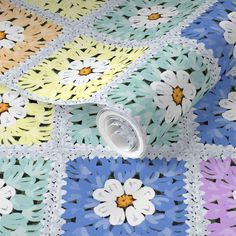 a multicolored crocheted tablecloth with flowers on it