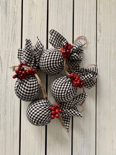 four black and white checkered fabric ornaments with red berries hanging from them on a wooden surface