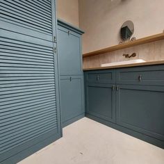 an empty bathroom with blue cabinets and white counter tops on the wall, along with a sink