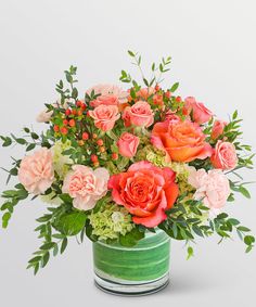 a green vase filled with pink and orange flowers