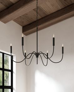 a chandelier hanging from the ceiling in a room with windows and wooden beams