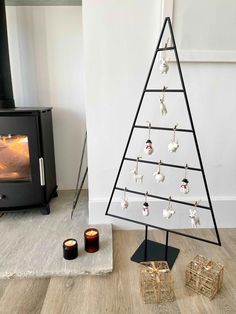 a small christmas tree with pearls hanging from it's sides in front of a wood burning stove