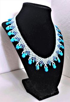 a necklace with blue beads is displayed on a mannequin