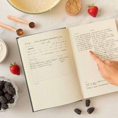 an open book with writing on it next to berries and other ingredients