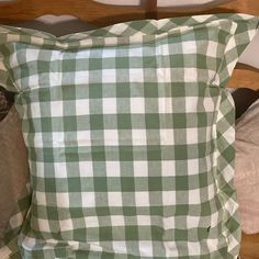 a green and white checkered pillow sitting on top of a bed