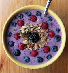 a bowl filled with fruit and granola on top of a wooden table