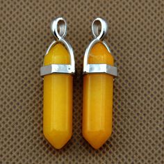 two yellow glass beads with silver clasps on a brown surface, one is shaped like a rectangle and the other is shaped like a rectangle