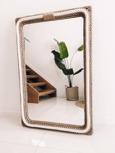 a mirror that is sitting on the floor next to a potted plant and stairs