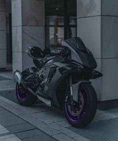 a black and purple motorcycle parked on the side of a street next to a building