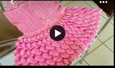 a pink crocheted blanket sitting on top of a table next to a mirror