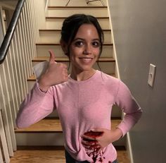 a woman giving the thumbs up while standing in front of stairs with blood on her shirt