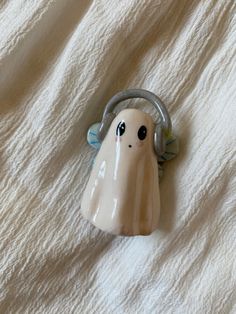 a ceramic toy with headphones on top of a white bed sheet in the shape of a ghost