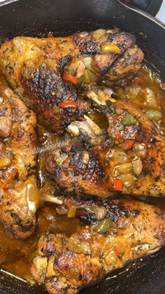 some chicken is cooking in a skillet on top of a stove burner with peppers and onions