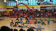 a group of people standing on top of a basketball court in front of an audience