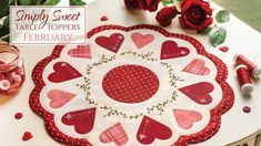 a red and white plate with hearts on it sitting next to some candles and flowers