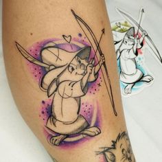 a tattoo on the leg of a woman with an arrow in her hand and a cat holding a bow