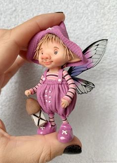 a hand holding a small figurine of a little fairy