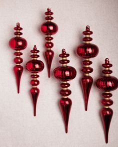 seven red glass vases are lined up against a white background