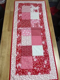 the table runner is made with red and white quilts, which are on top of a wooden table