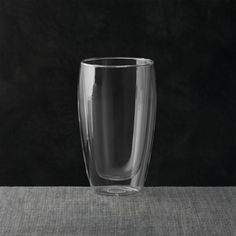 a glass sitting on top of a table next to a black wall and flooring