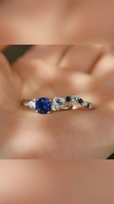 a woman's hand holding an engagement ring with two blue sapphires on it