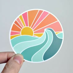 a hand holding up a sticker with the sun and water