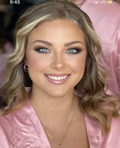 a woman with blonde hair and blue eyes wearing a pink robe smiling at the camera