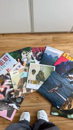 a person standing on top of a wooden floor next to various magazine covers and magazines