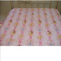 a pink bed with princesses on it in a small child's crib