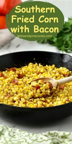 a skillet filled with corn and bacon on top of a table next to tomatoes