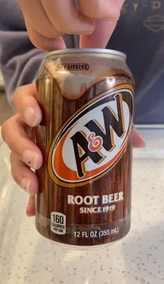 a person holding a can of root beer