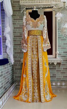 a yellow and white dress on display in front of a mirror with chandelier hanging from the ceiling