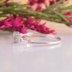 a close up of a ring on a table next to pink flowers and purple flowers