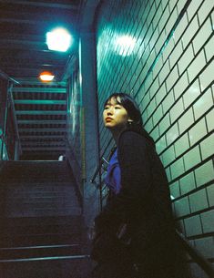 a woman standing in front of a stairwell at night