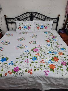 a bed with white sheets and colorful flowers on it