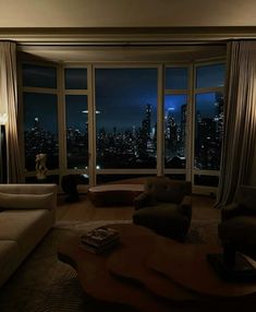 a living room filled with furniture and large windows overlooking the city lights at night time