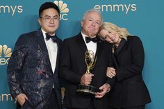 two men and a woman posing with an award