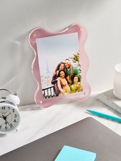 a photo frame sitting on top of a desk next to an alarm clock