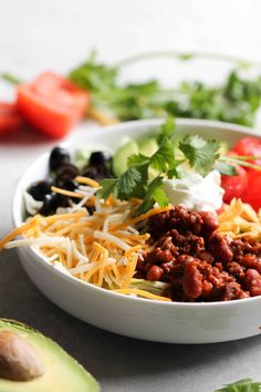 a white bowl filled with taco salad next to an avocado