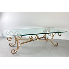 a glass and gold coffee table with scroll designs