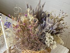 a basket filled with lots of flowers on top of a table next to two candles