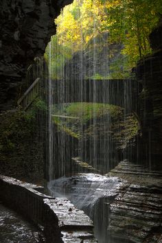 a waterfall in the middle of a forest with lots of water falling from it's sides