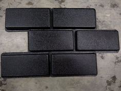 four pieces of black plastic sitting on top of a cement floor