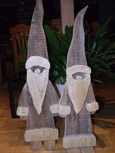 two wooden gnome figurines sitting next to each other on top of a hard wood floor